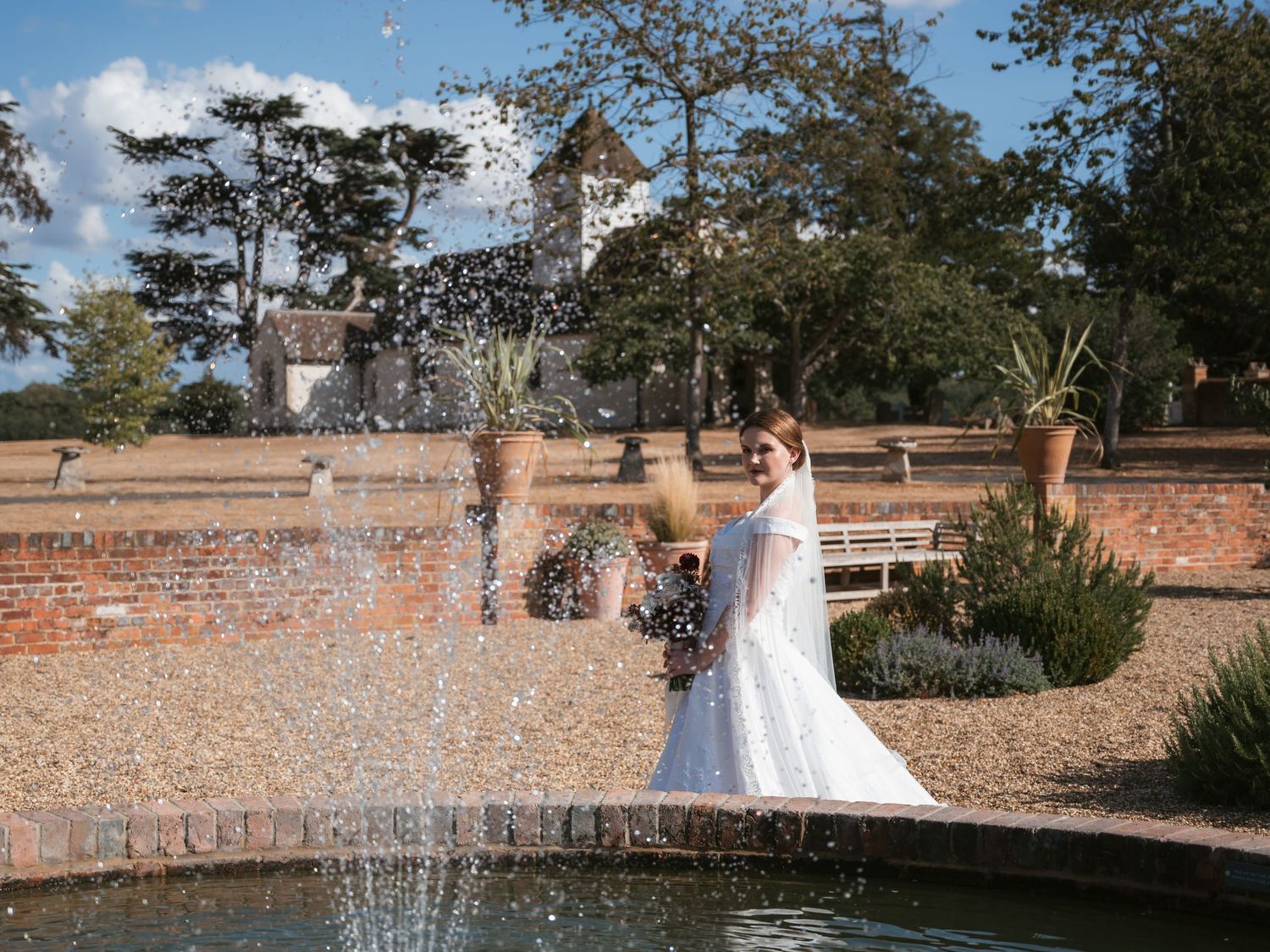 Bride at Wasing Park with church in background and water fountain in foreground
