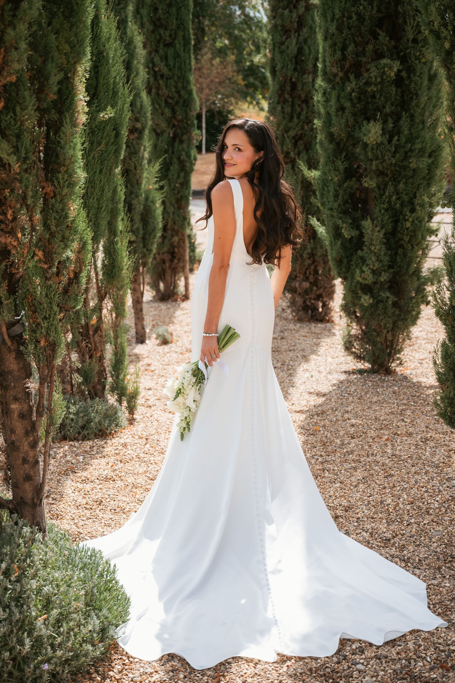 Bridal portrait between cypress trees at Wasing Park featuring glam dress by Stella York
