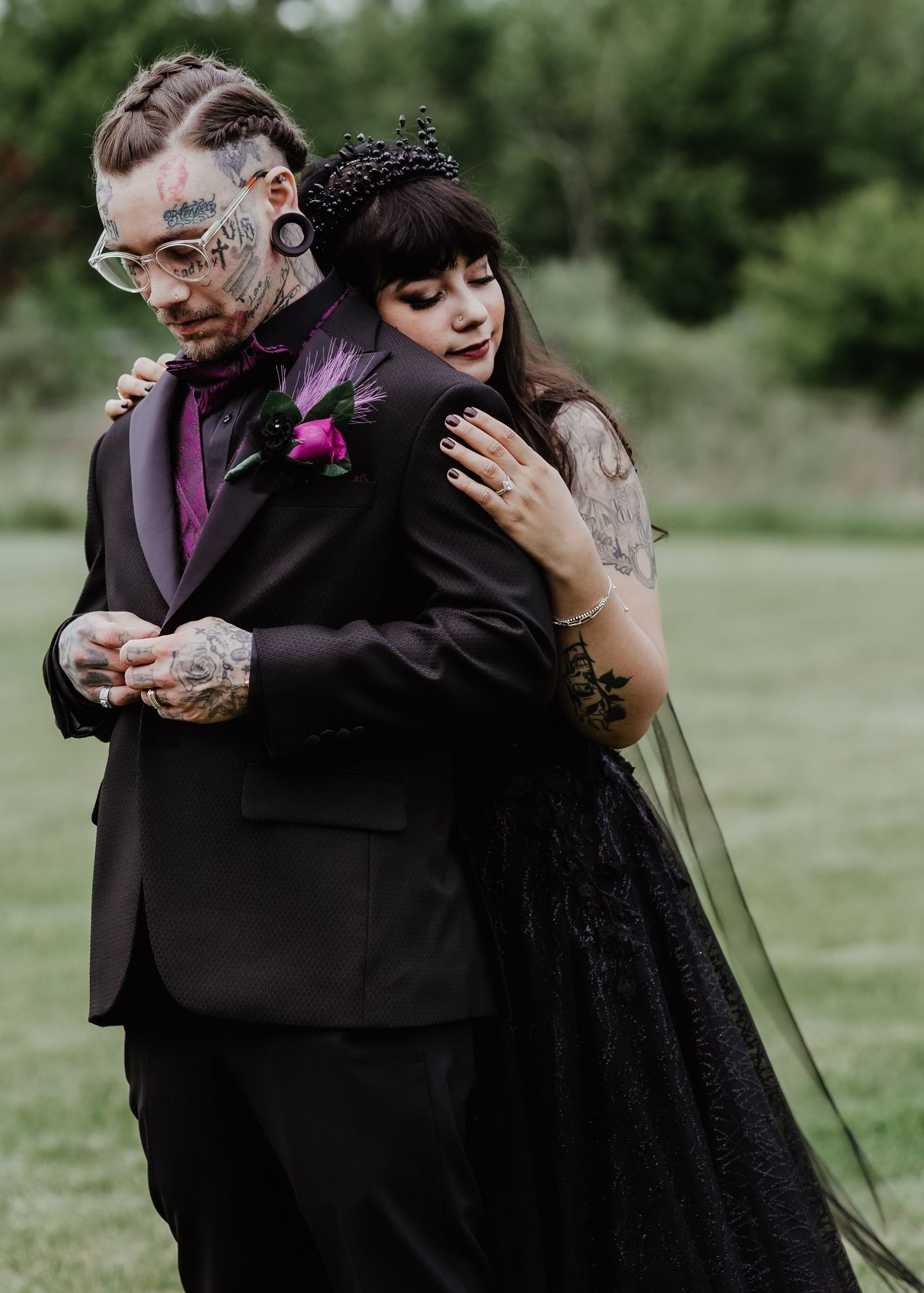 Wedding couple embracing outdoors, with the bride wearing a flowing black dress