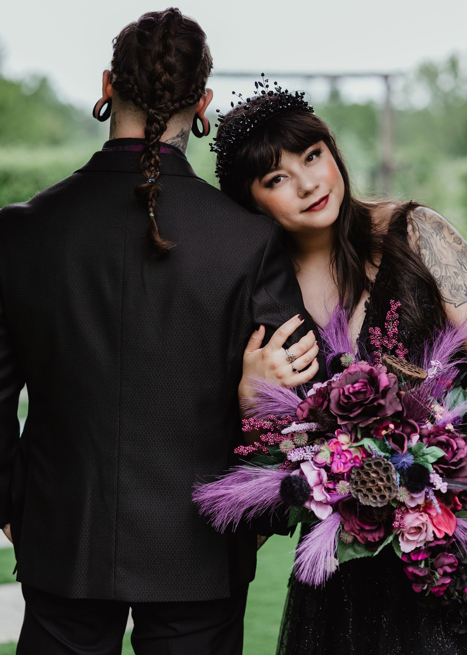 Couple embracing during an outdoor wedding with a bouquet of flowers