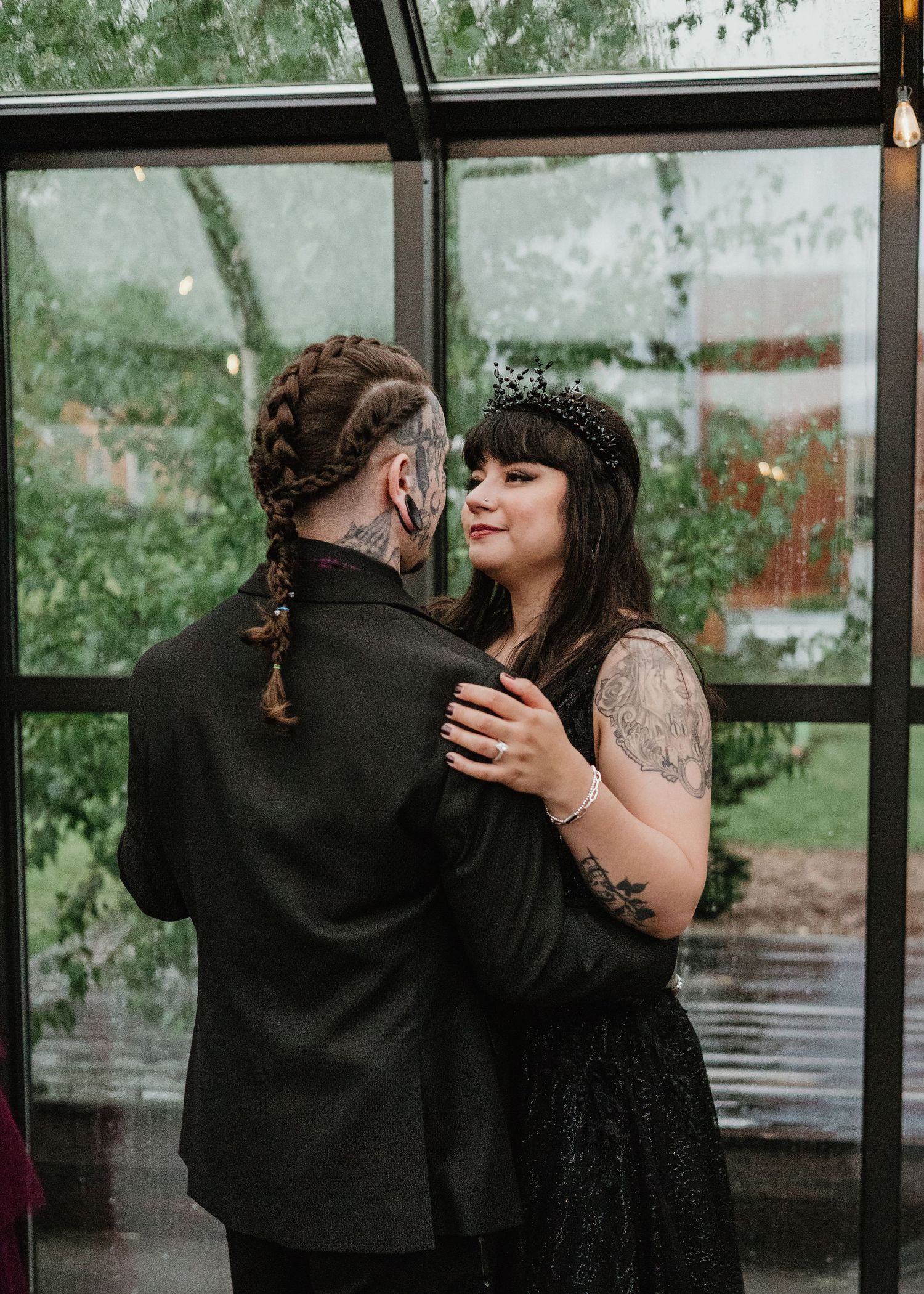 Couple embracing in a greenhouse surrounded by windows and greenery