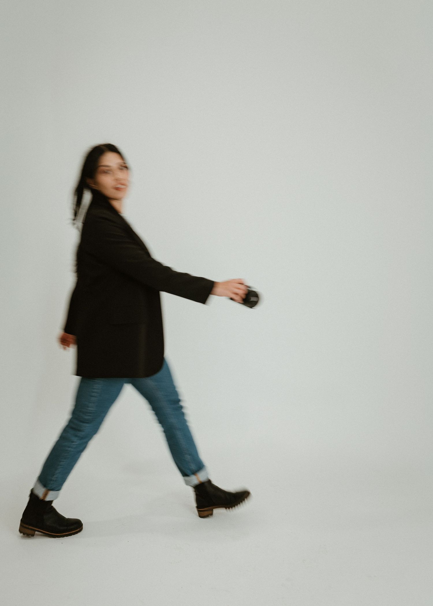 Woman walking in a black jacket and jeans during a studio portrait session