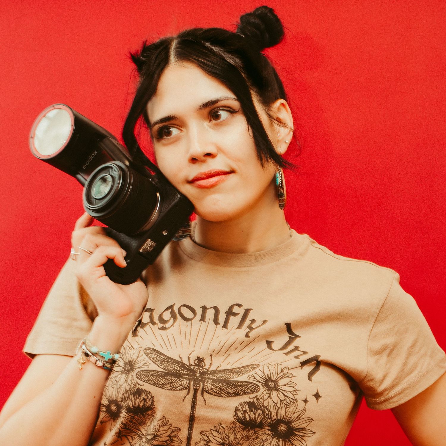 Editorial portrait of a woman holding a camera against a vivid red background