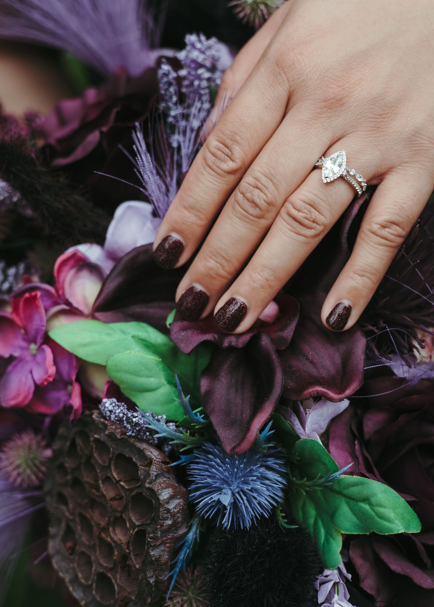 Close-up of a bride's hand and wedding ring resting on a colorful bouquet