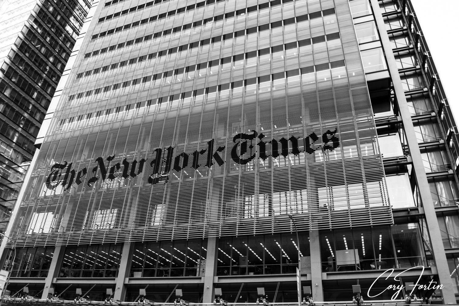 Black and white photo of The New York Times building facade with iconic logo in Midtown Manhattan.