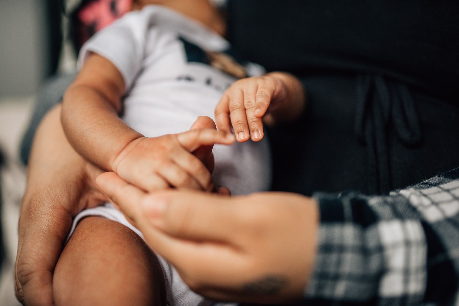Close-up of a baby grasping an adult finger, symbolizing bonding and parental love.