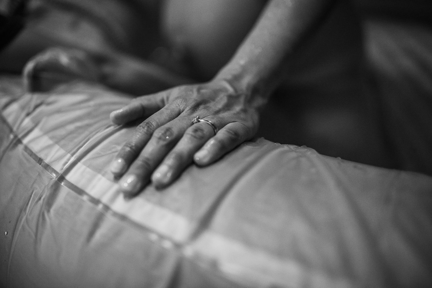 Black and white photo of hands resting on a massage table during a therapeutic massage session.