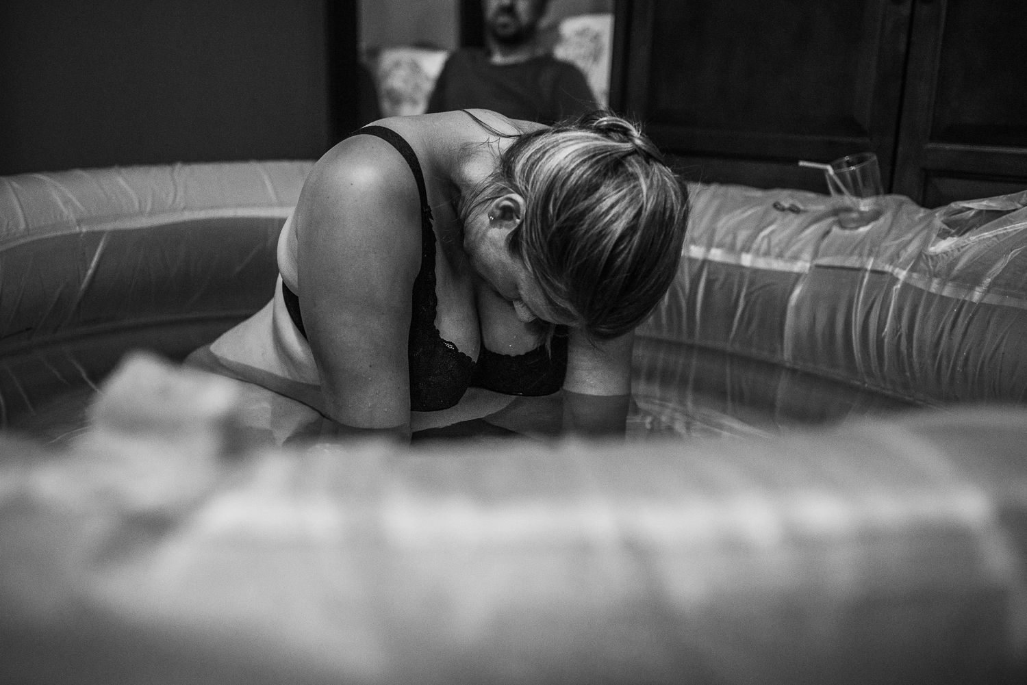 Black and white photo of a woman laboring in a birthing pool during a home water birth.