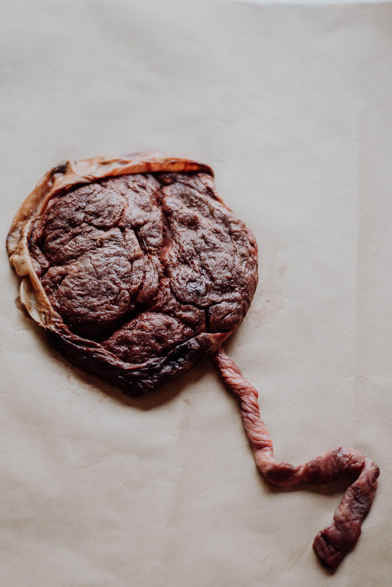Close-up of a cooked beef steak on parchment paper, showing rich brown seared texture with a thin strip of meat.