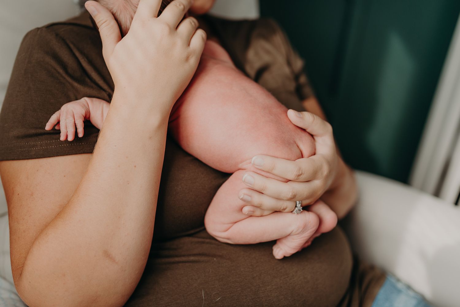 Close-up of parents cradling their newborn baby, showcasing tiny hands and feet in a tender moment.