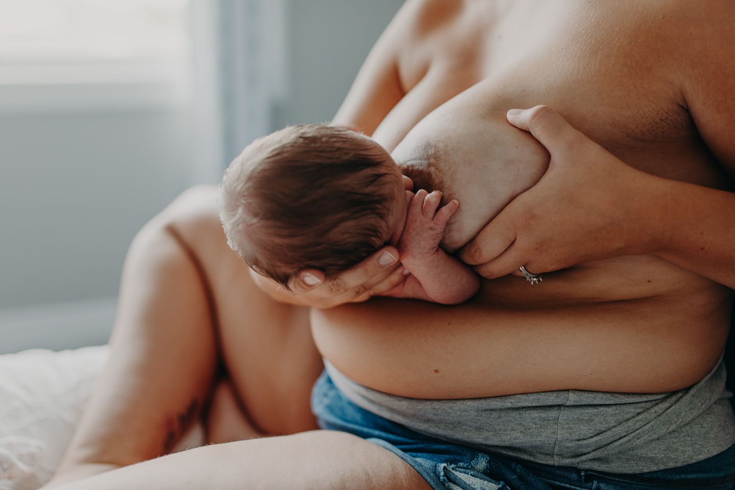 Mother breastfeeding her newborn baby, skin-to-skin bonding moment captured in soft natural light.