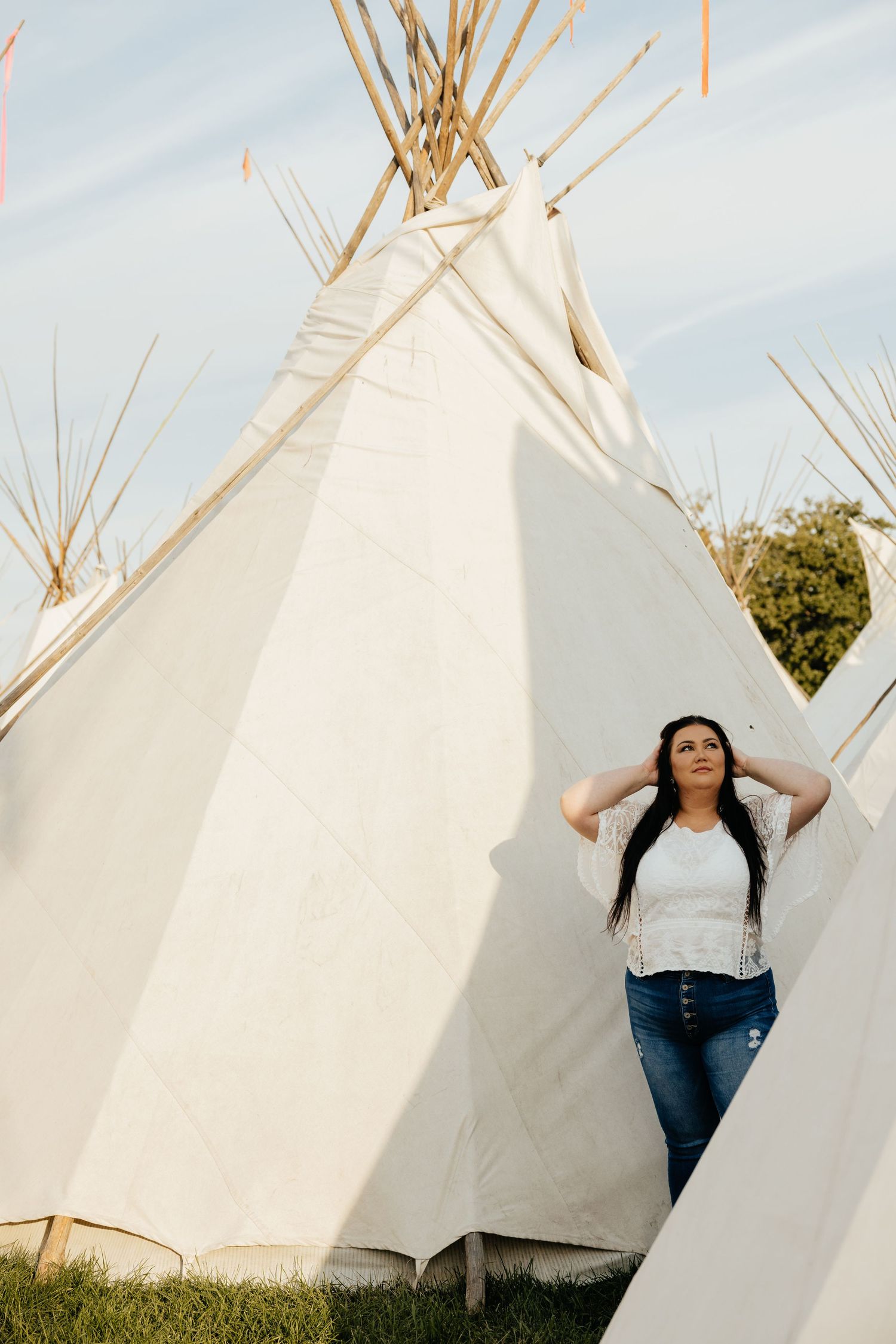 Portrait beside rustic teepees in grassy Oregon field, lifestyle photography session