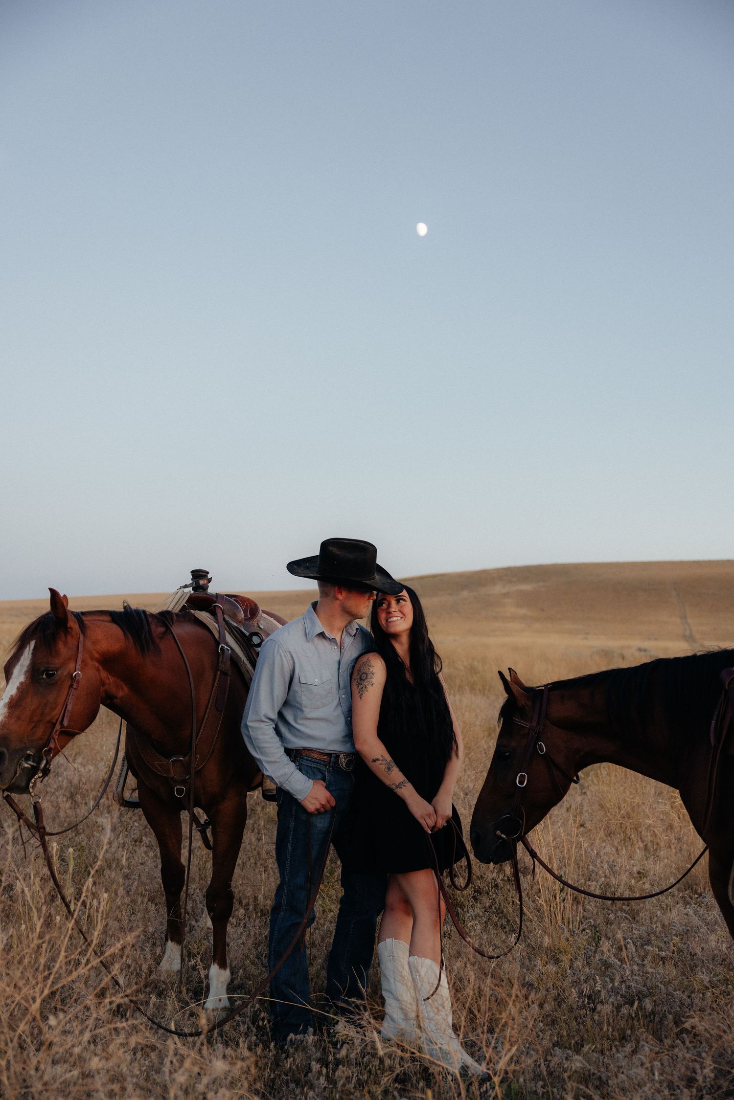 Couple with horses under moonlit sky, rustic countryside engagement session in Eastern Oregon