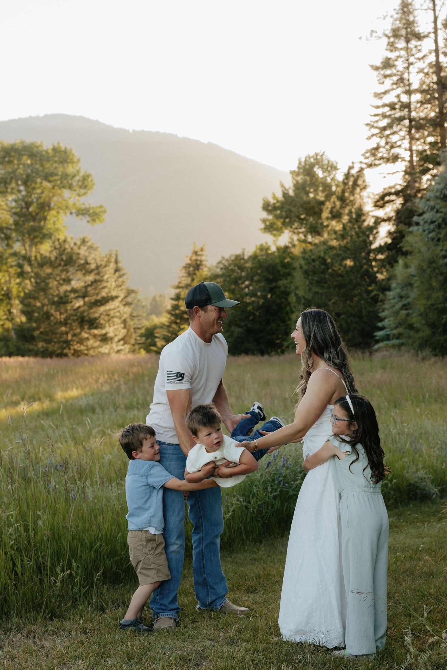 Family portrait in grassy Oregon field with mountains, Baker City lifestyle photography