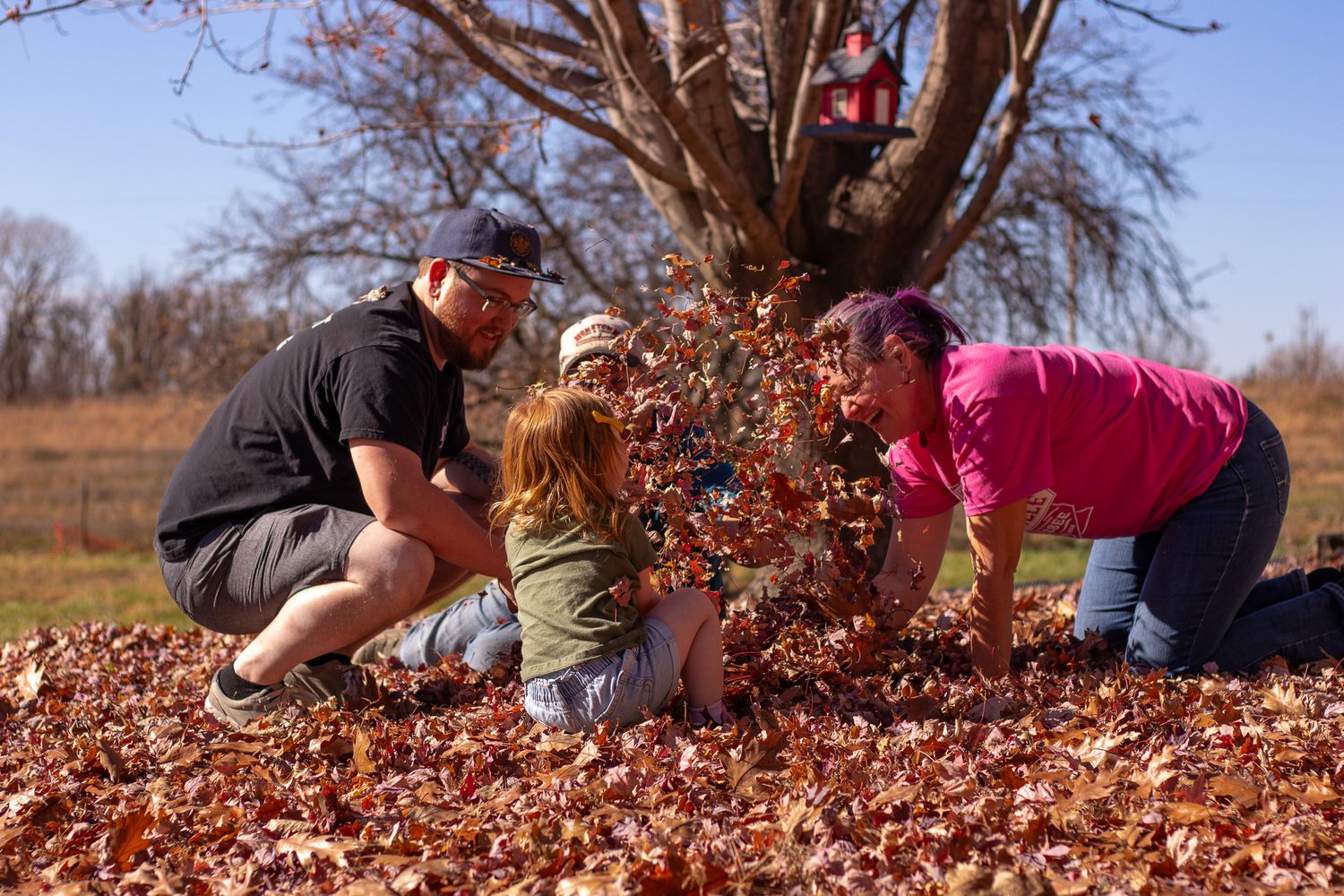 A family playing in the fall leaves.
