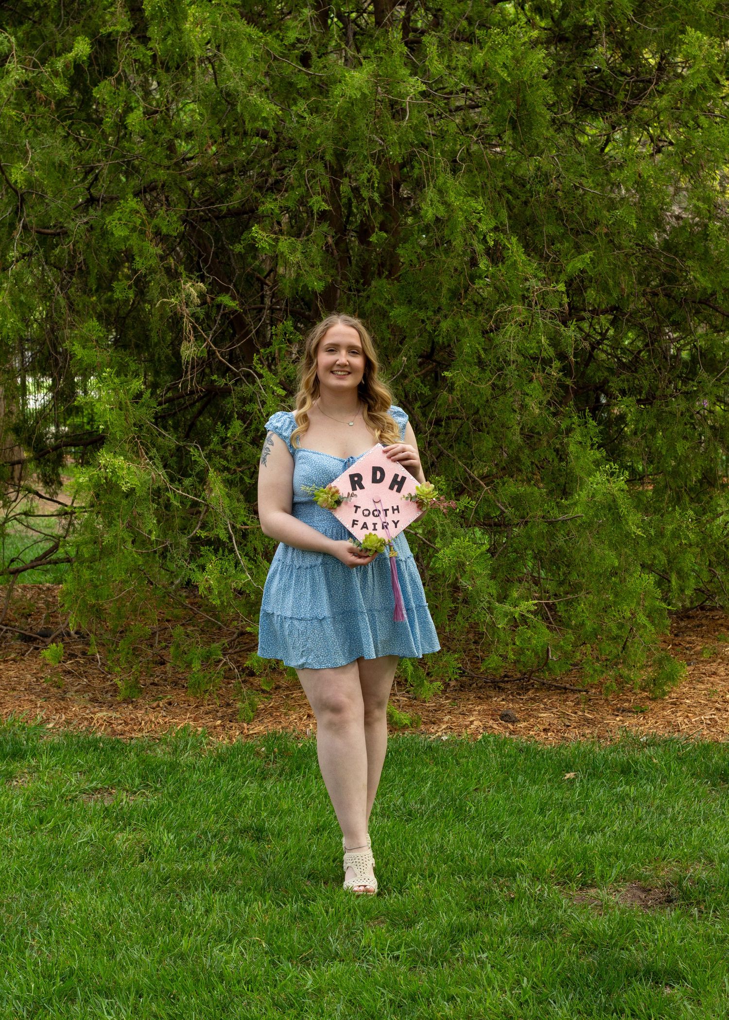 A girl holding her decorated graduation cap outside.