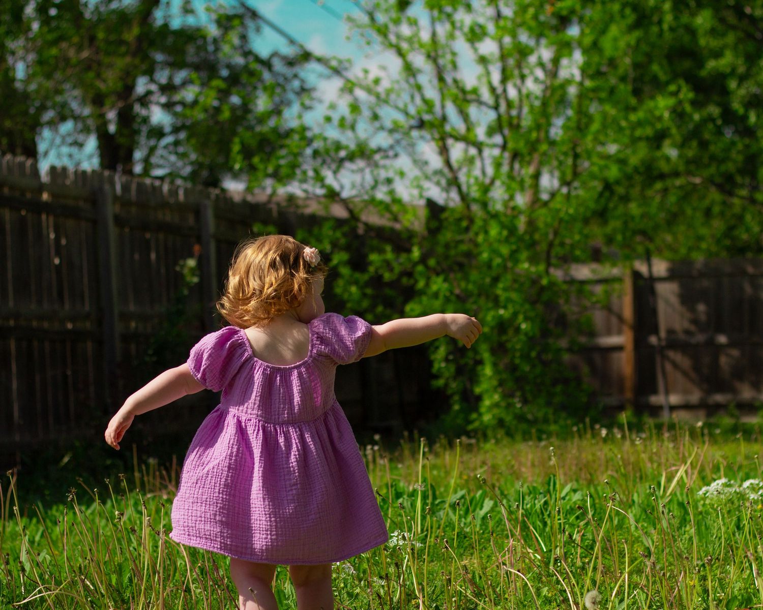 A girl in a purple dress playing outside.