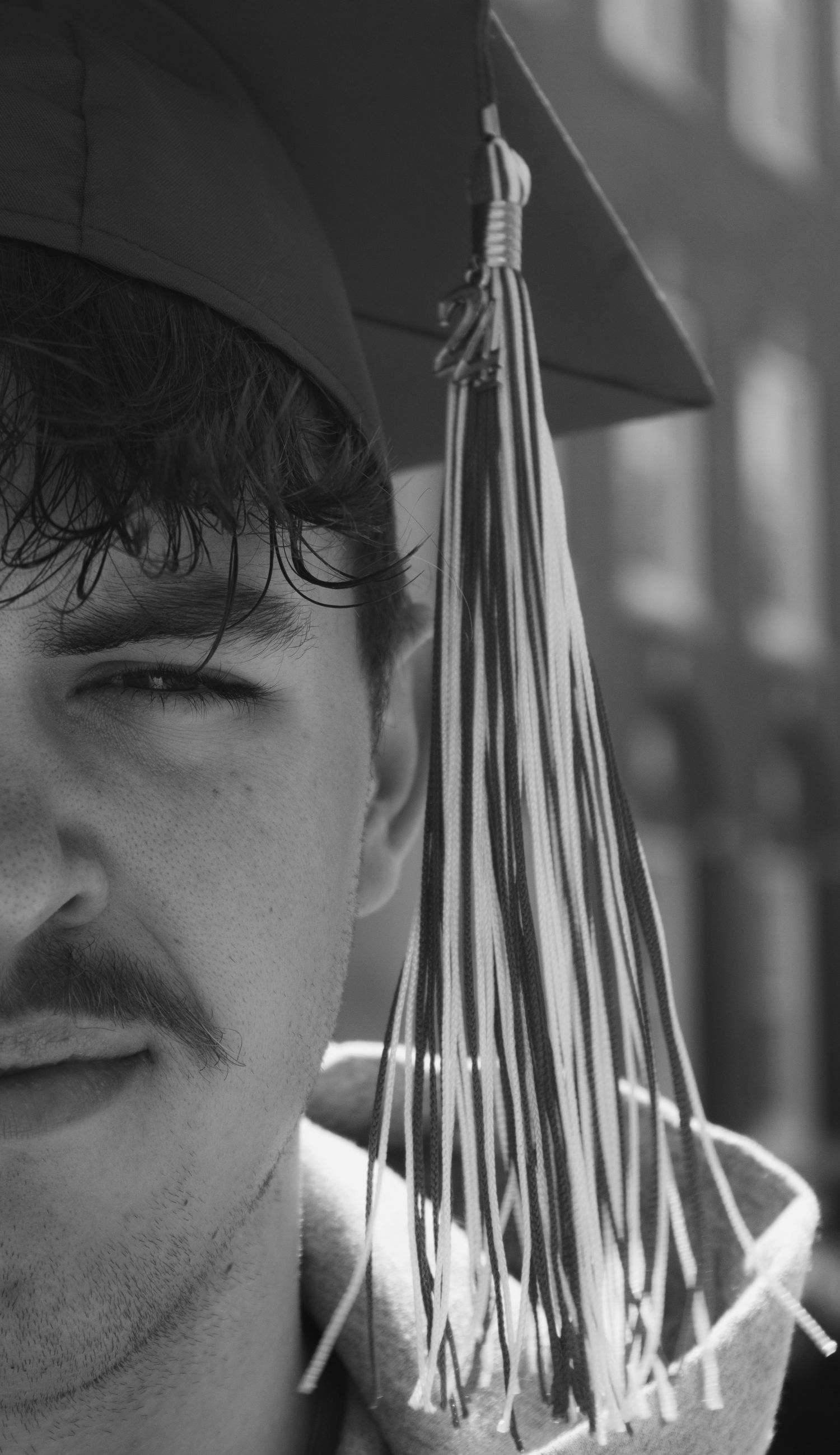 A close up of a boy wearing a graduation cap in black and white.