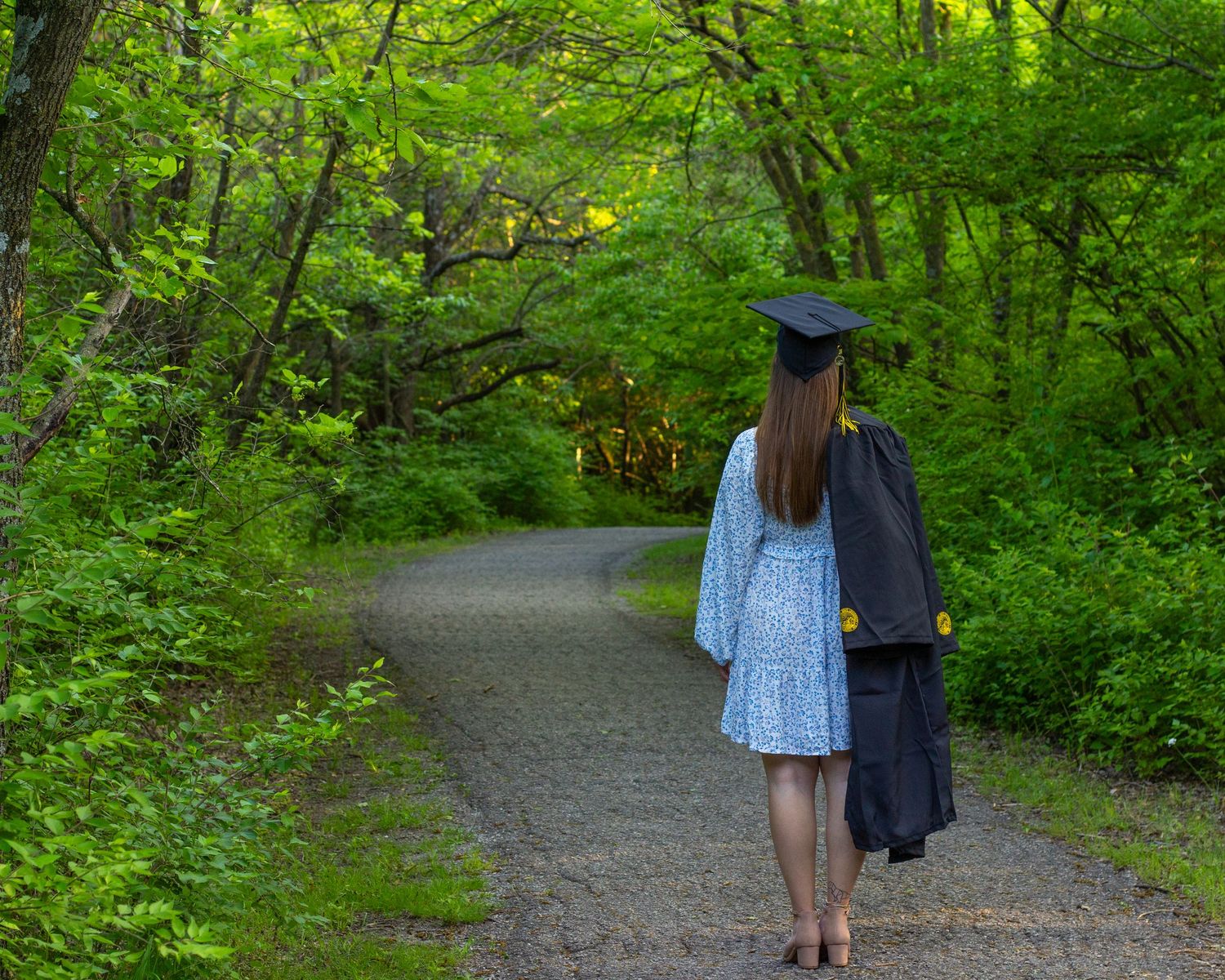 A girl in a graduation cap walking down a path.