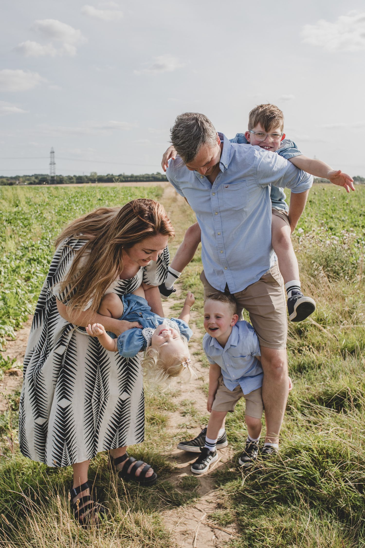 Family enjoying playful moment together in sunny summer field.
