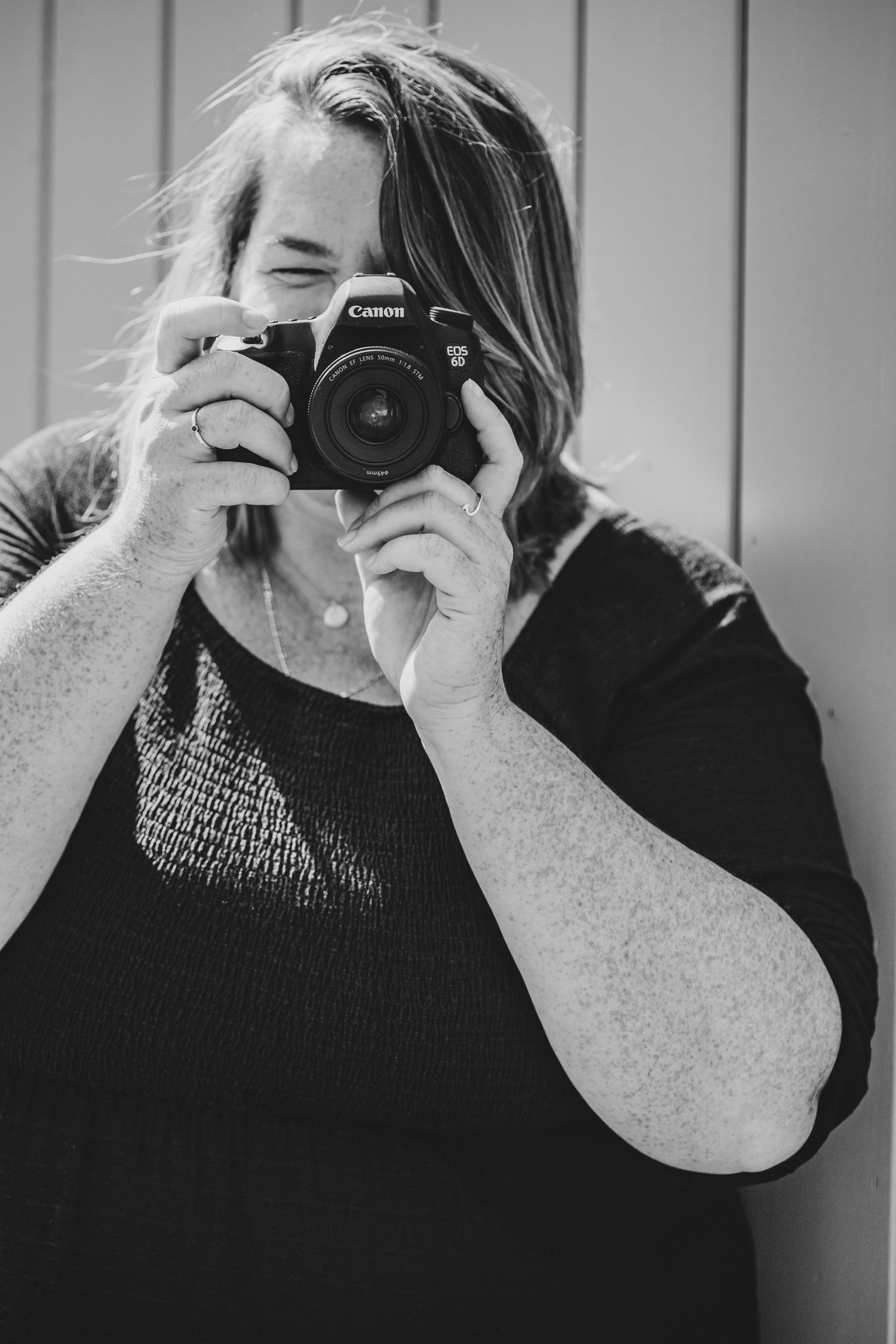 Black and white portrait of photographer using Canon DSLR camera.