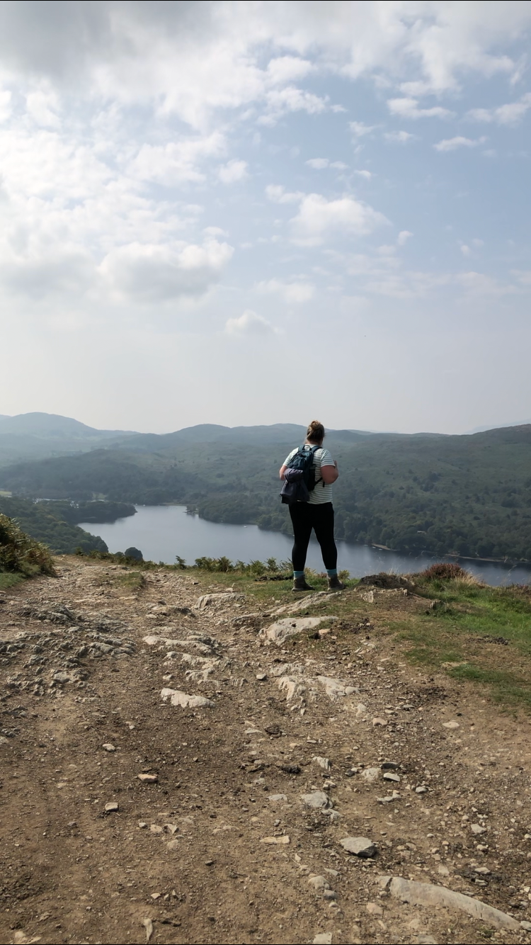 Hiker overlooking a scenic mountain lake vista from a rocky overlook point.