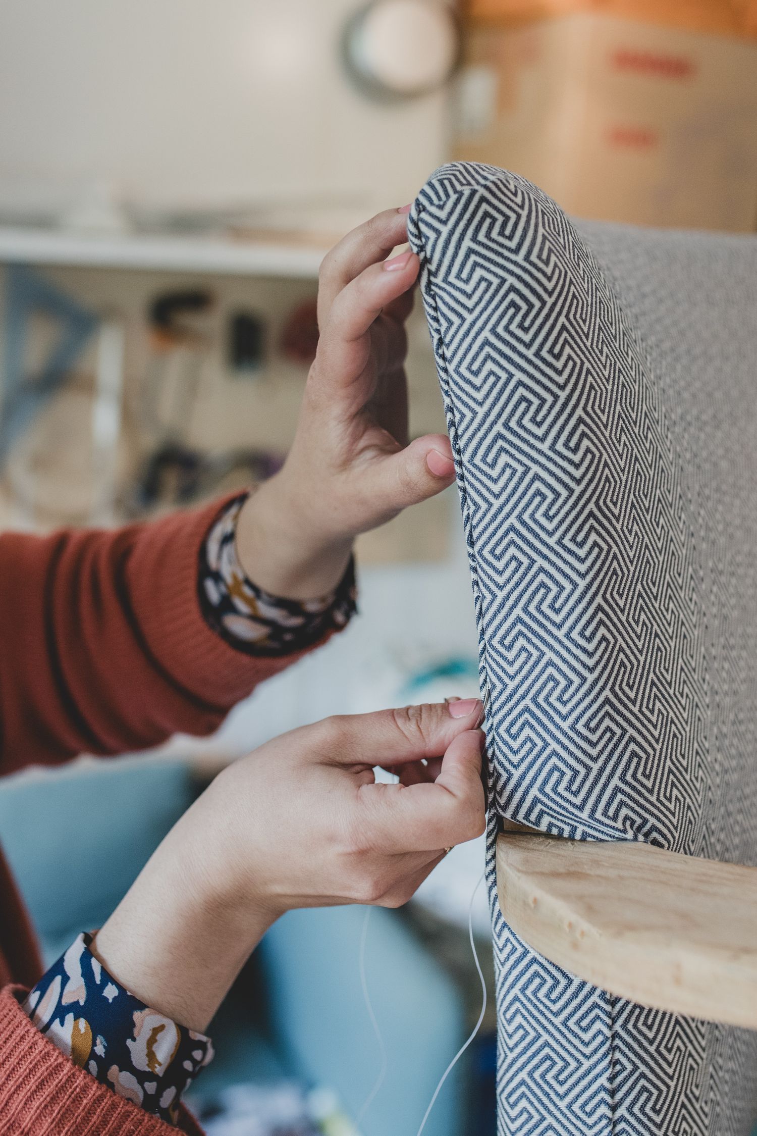 Hands holding geometric patterned fabric showing upholstery detail.