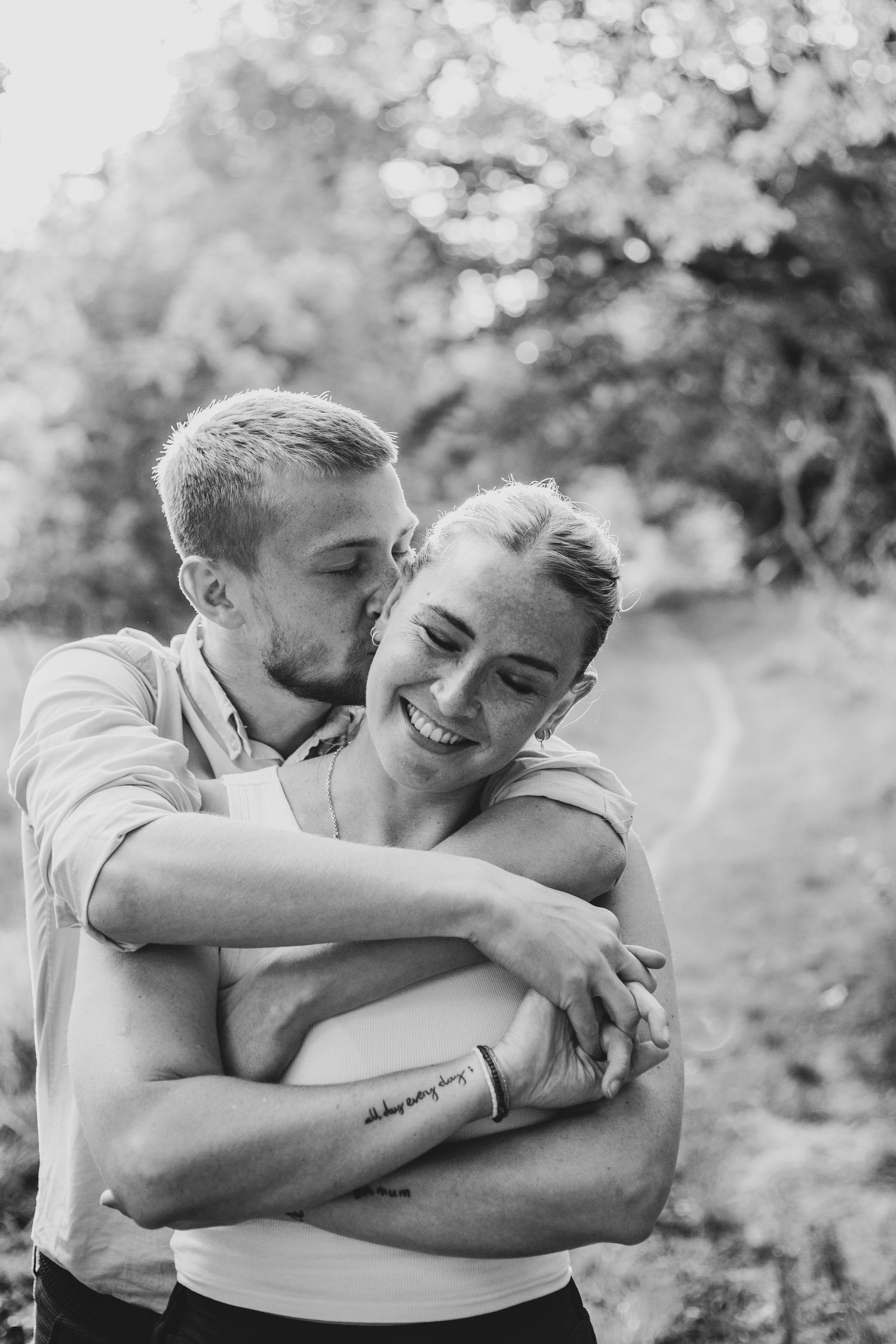 Black and white intimate portrait of loving couple embracing outdoors.