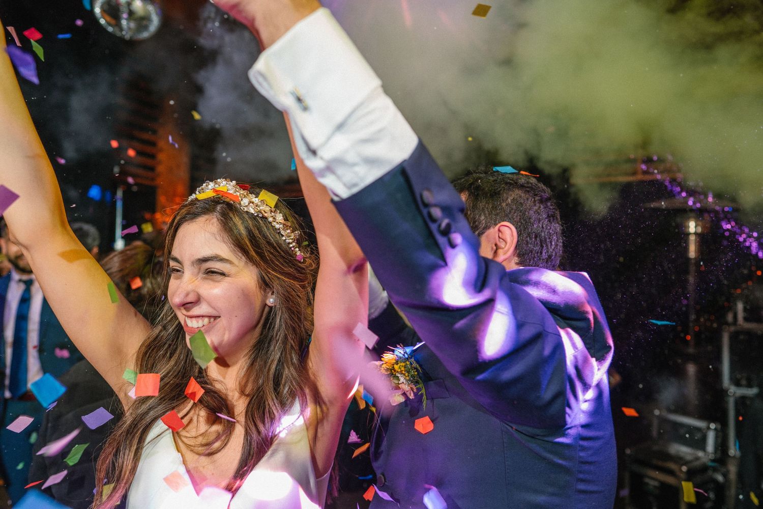 Wedding celebration with colorful lights and smoke effects on the dance floor.