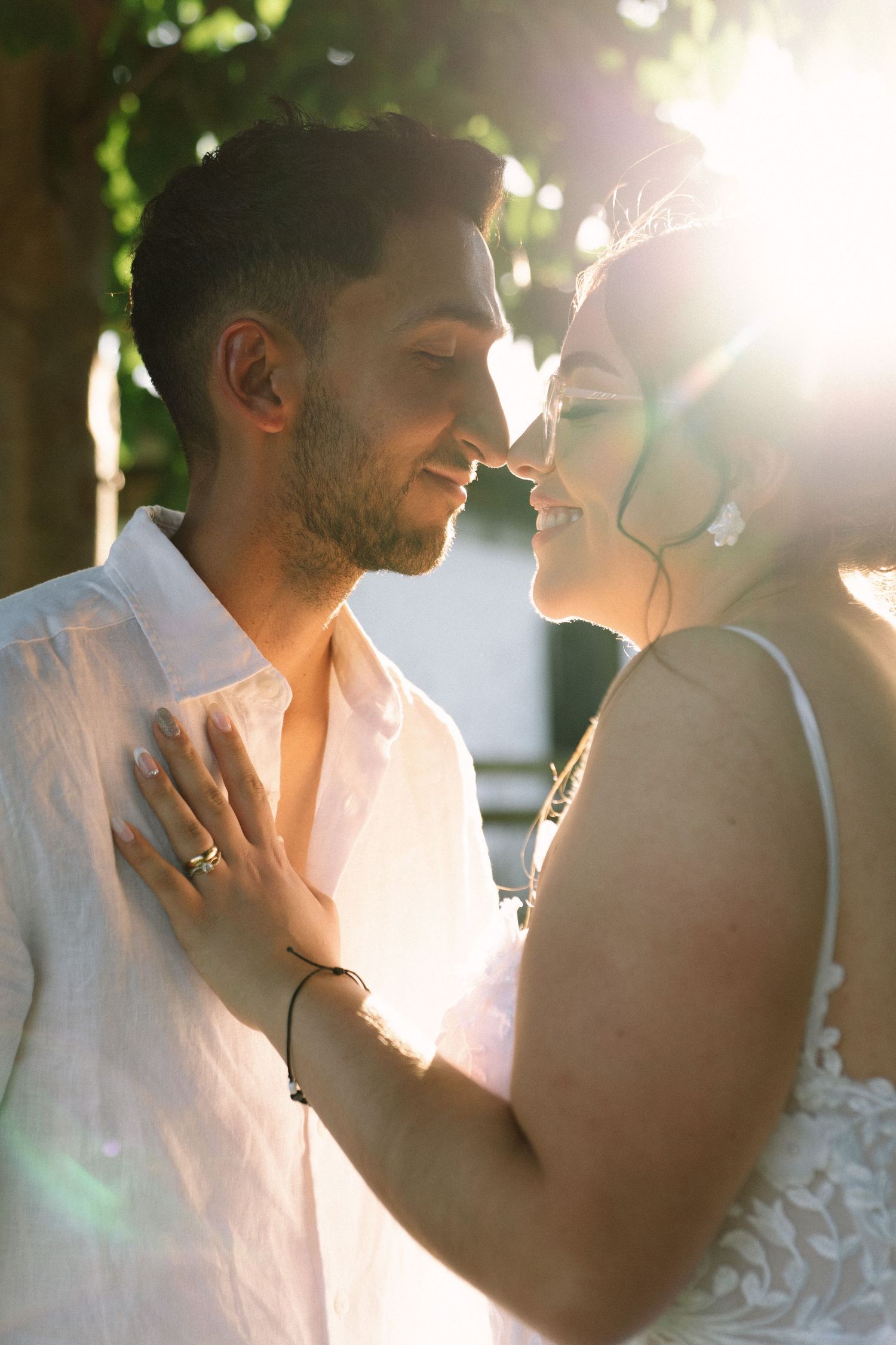 Bride and groom share romantic moment in golden sunset light at outdoor wedding.