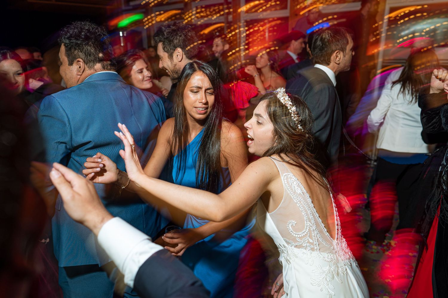 Wedding guests dancing energetically under colorful lights during the reception.