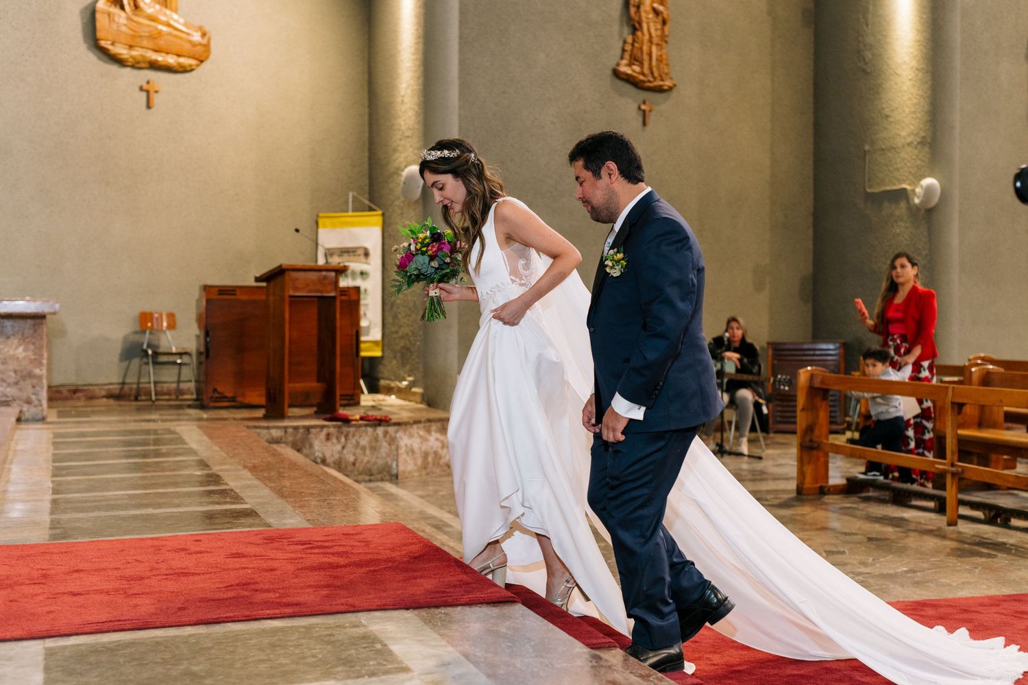 A couple walks down the red-carpeted church aisle together after their ceremony.