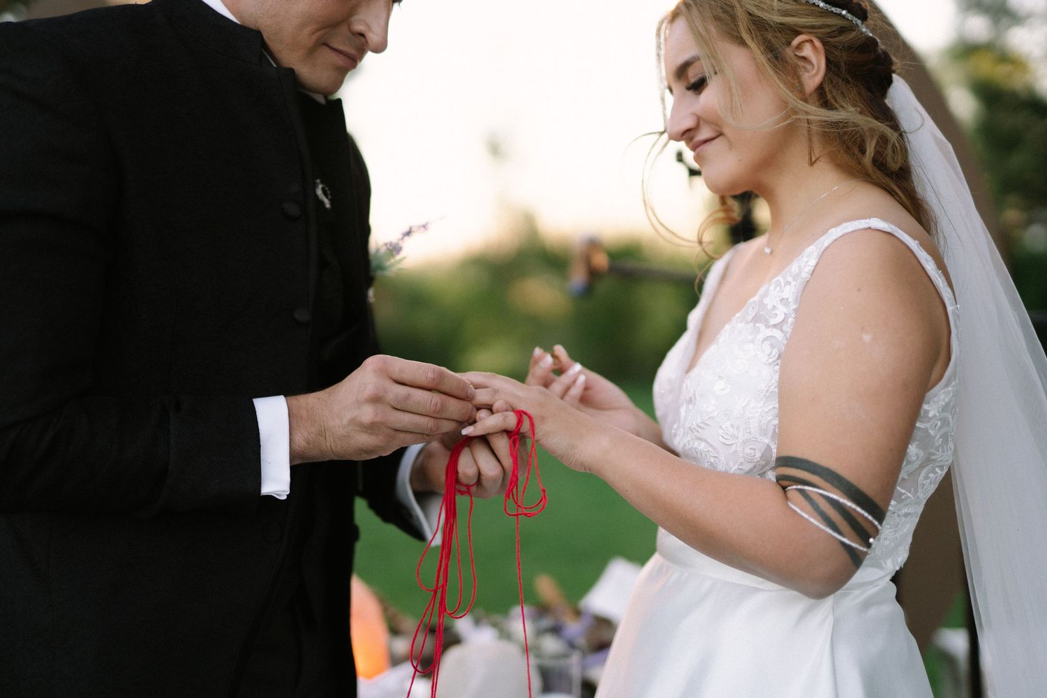 Close-up of a ring exchange moment during an outdoor wedding ceremony.