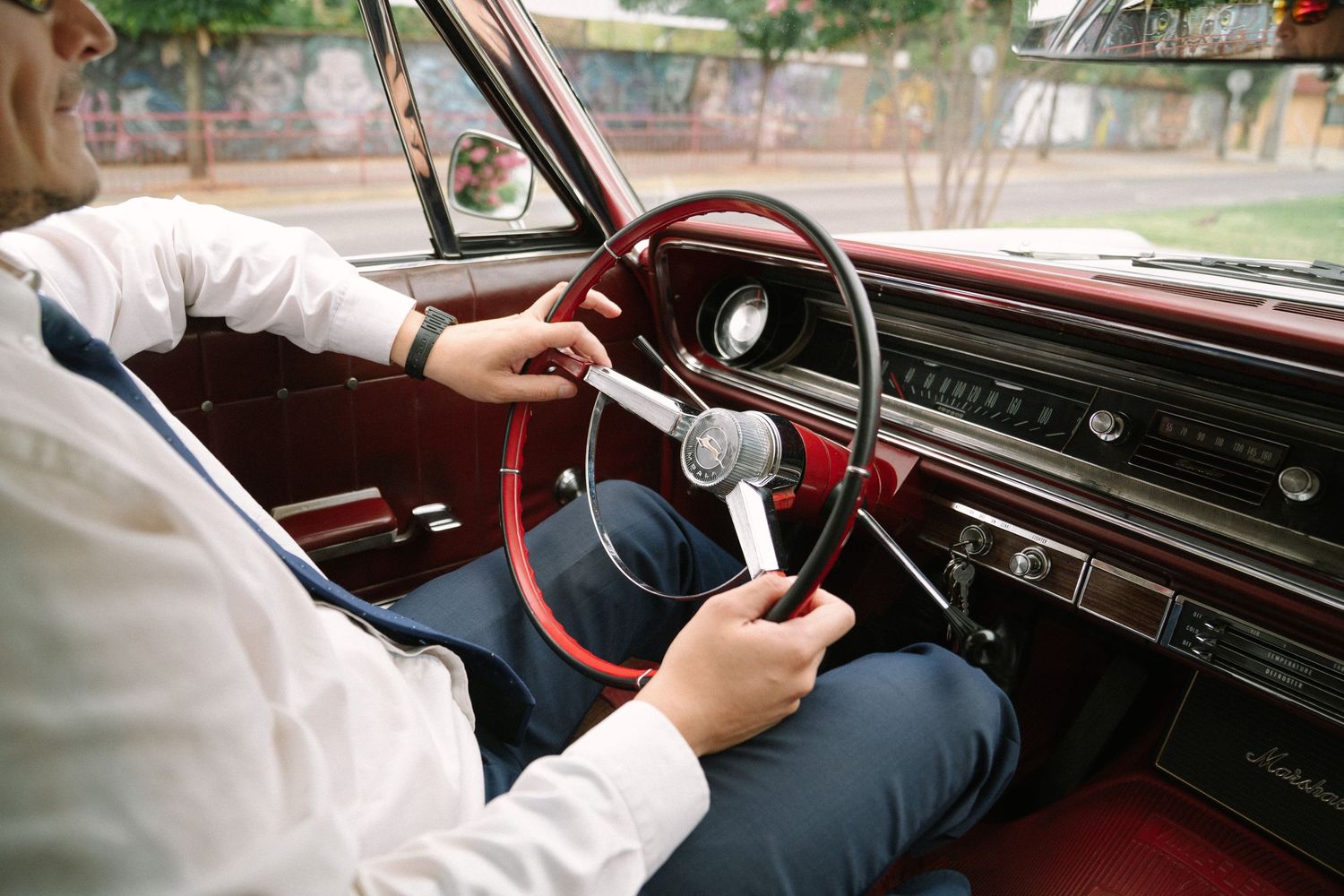 Close-up view of hands gripping and turning a vintage car's steering wheel.