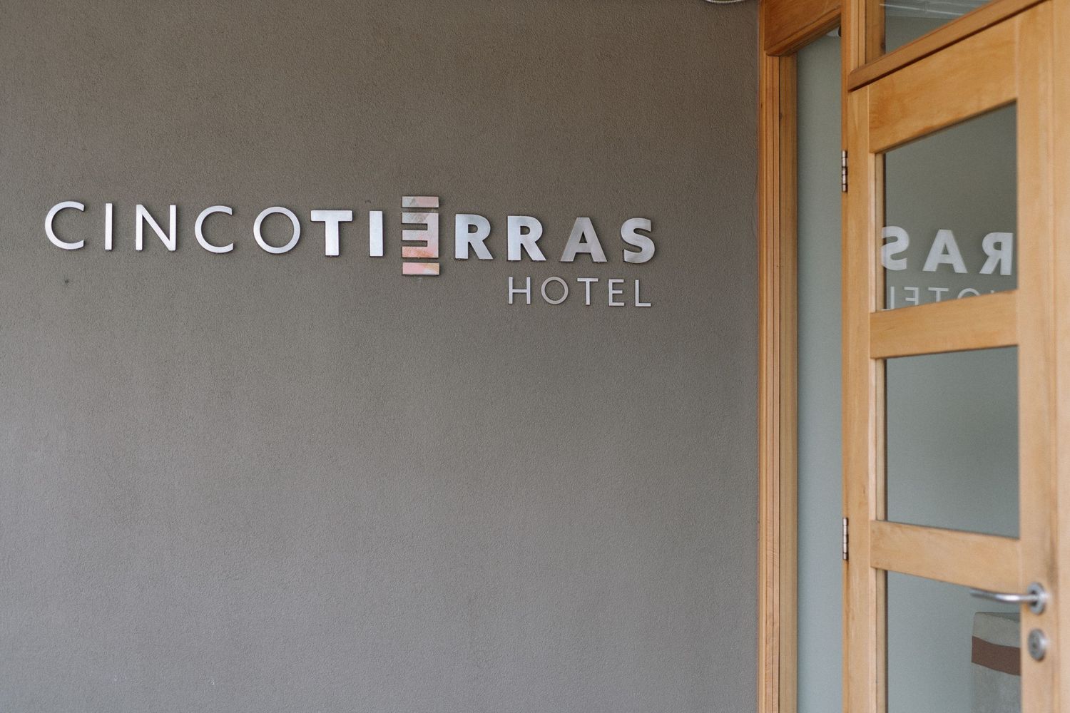 Exterior signage for Cinco Tierras Hotel mounted on a gray wall.