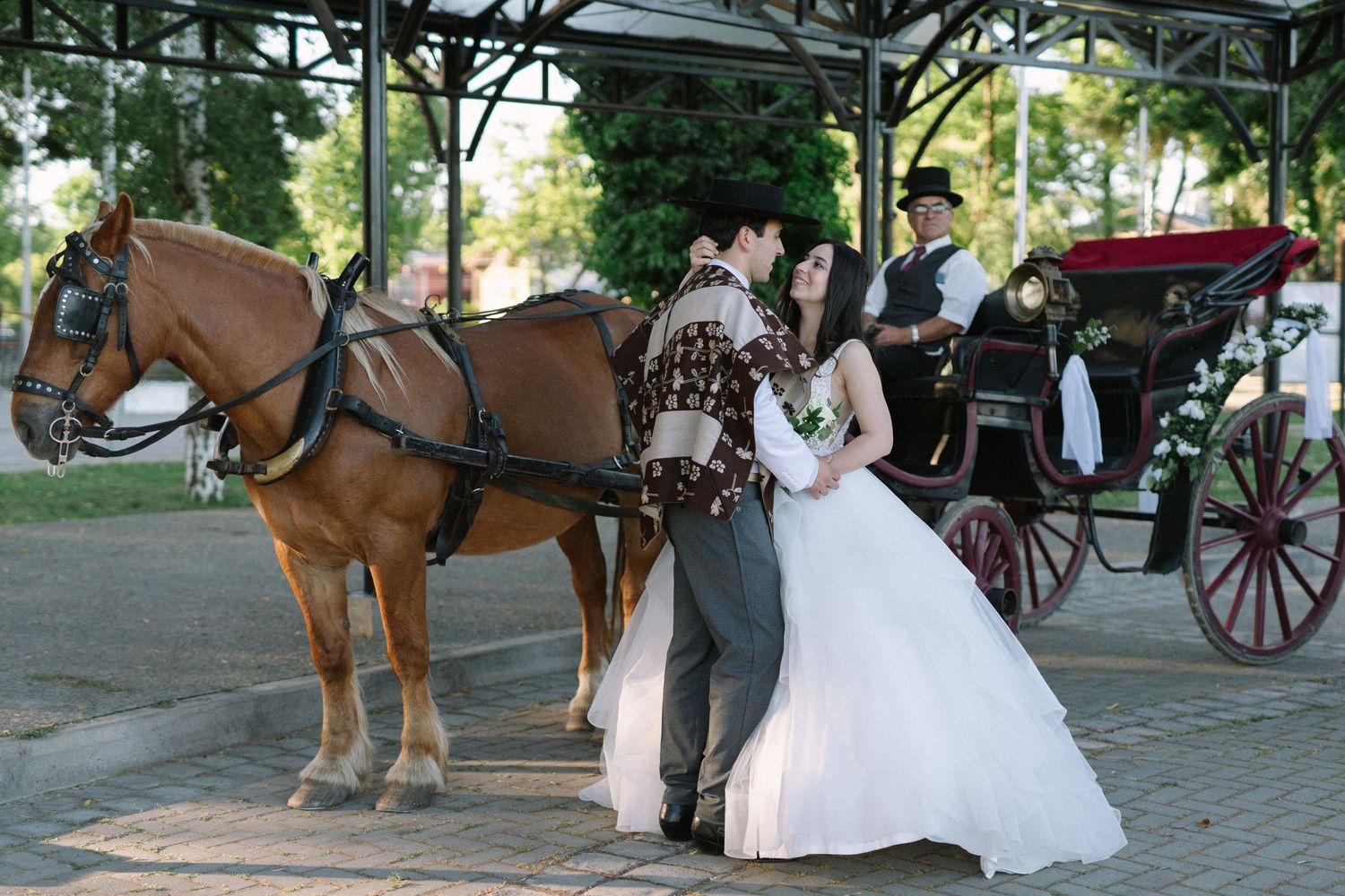 A beautiful white wedding dress contrasts with a rustic horse and carriage setting in an outdoor venue.