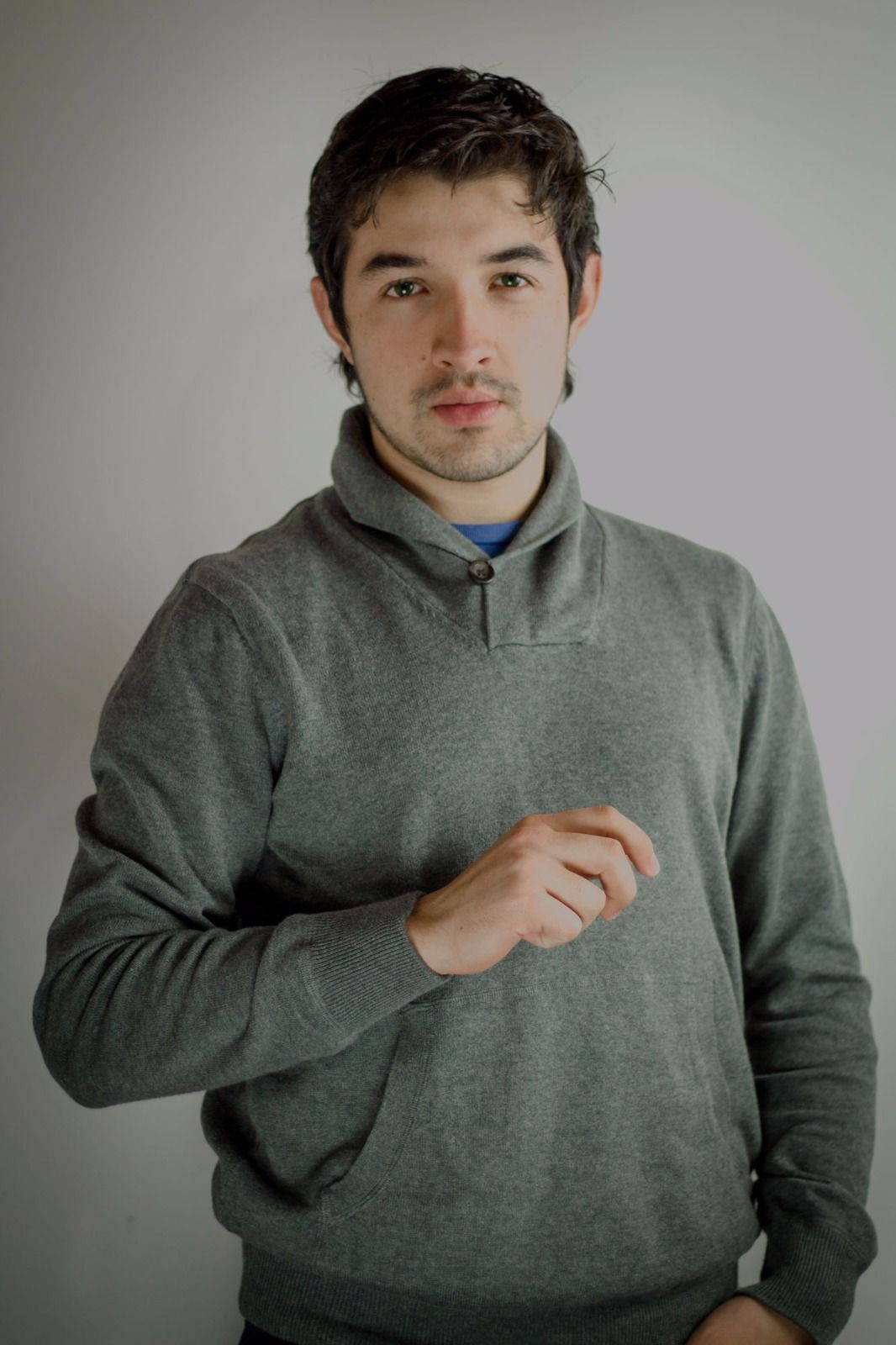 Portrait of person in grey pullover sweater against light background.