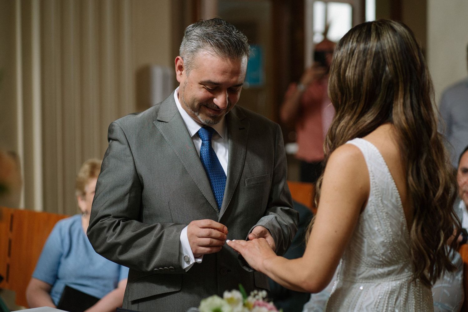 A tender moment during a ring exchange at an indoor wedding ceremony.