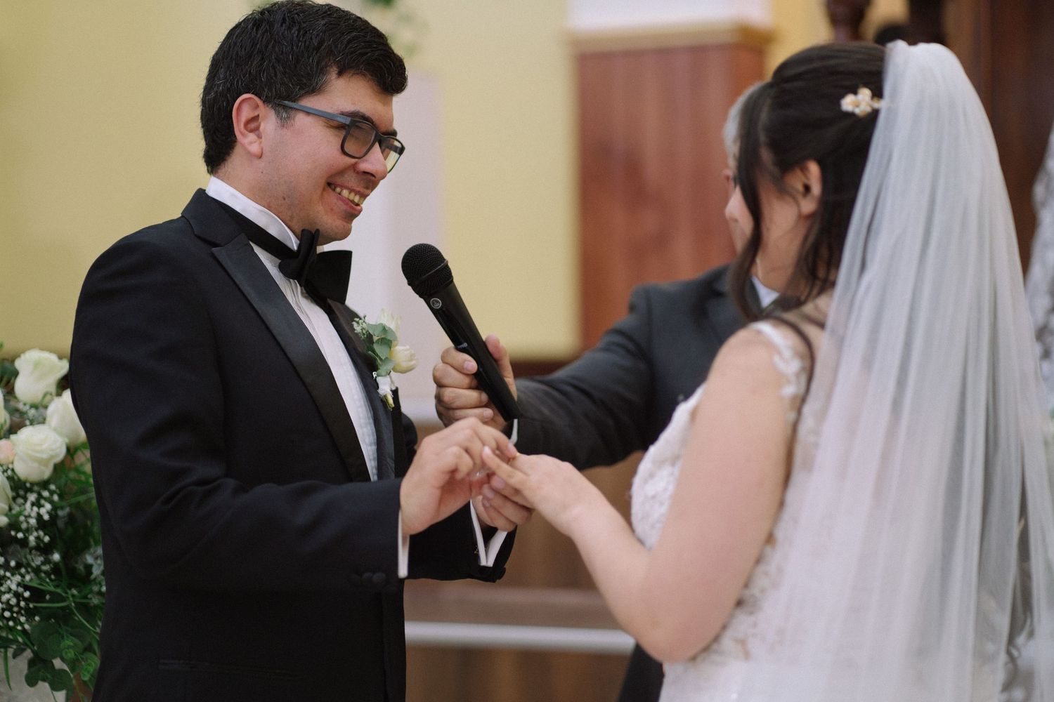 A heartfelt moment during wedding vows exchange with microphone at church altar.