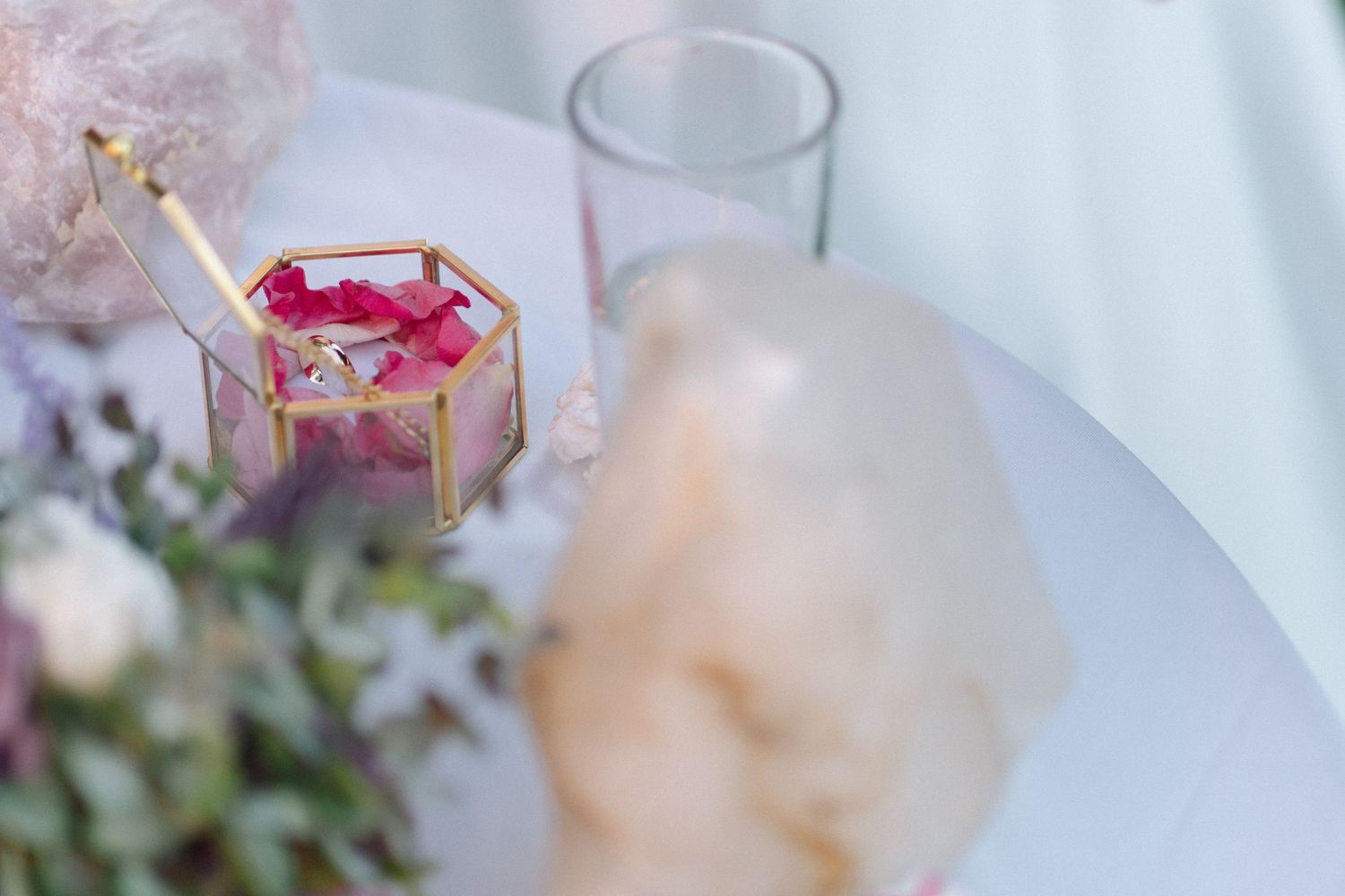 Wedding reception table detail with geometric candle holder and delicate floral arrangements.