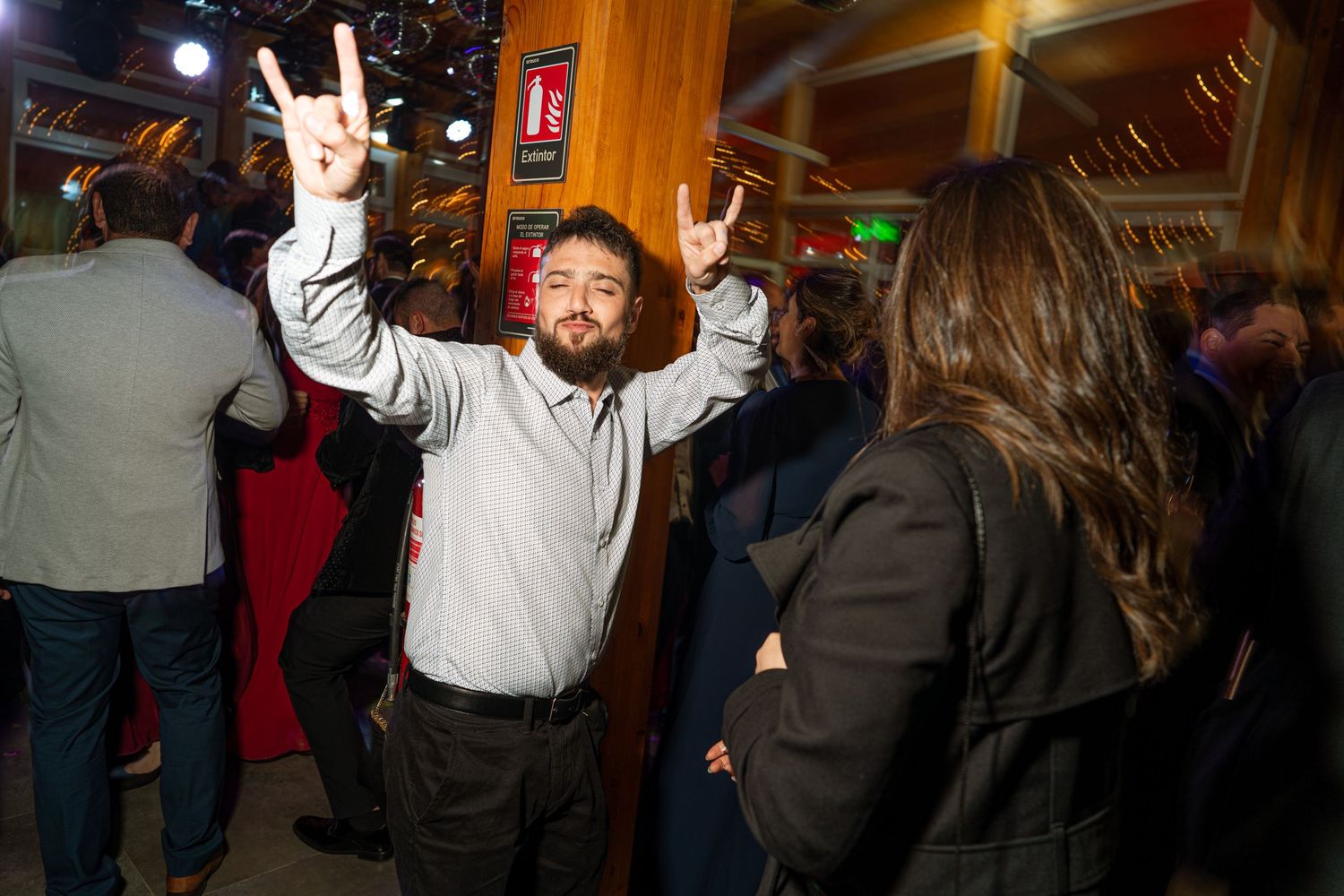 Party guest enthusiastically dancing with raised arms under venue lighting.