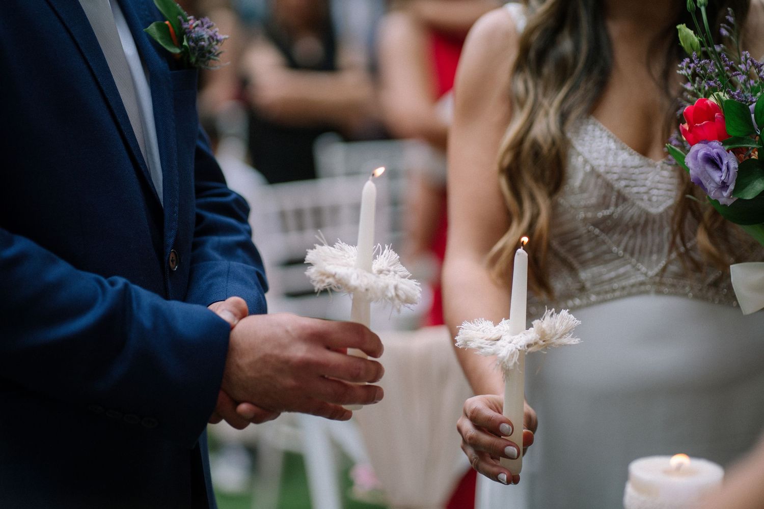 Close-up shot of couple holding lit unity candles during wedding ceremony.