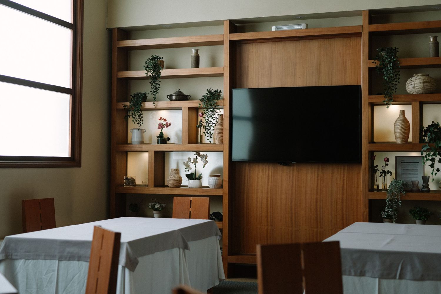 Modern dining room with built-in wooden shelving unit and wall-mounted TV.
