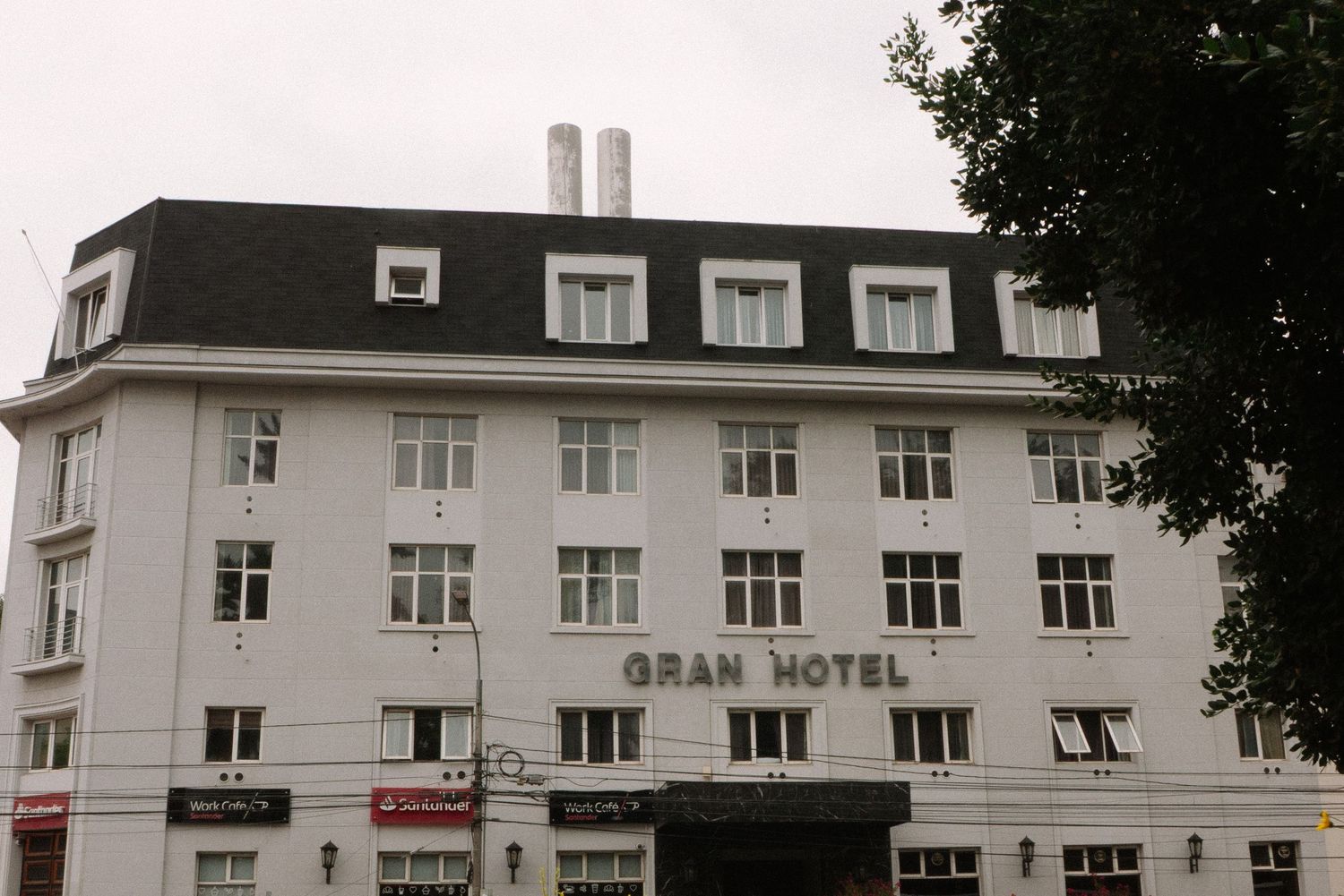 Historic white hotel building with multiple windows and 'GRAN HOTEL' signage stands prominently on a street corner.