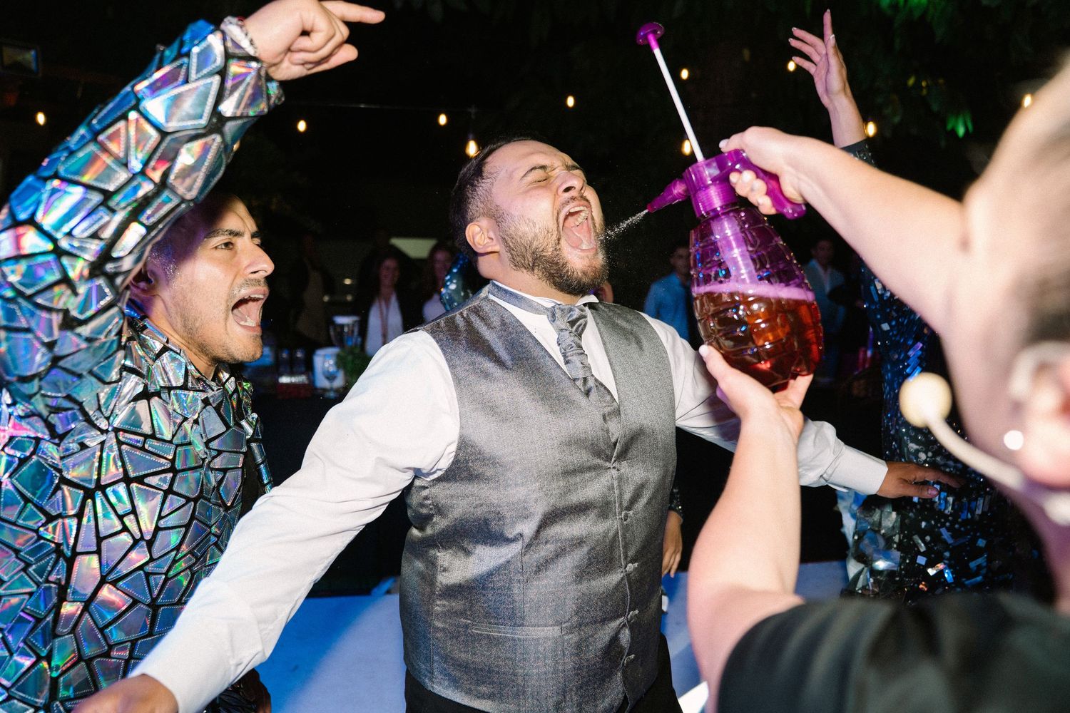 Groom celebrates joyfully with guests on the dance floor during a lively and colorful wedding reception party.