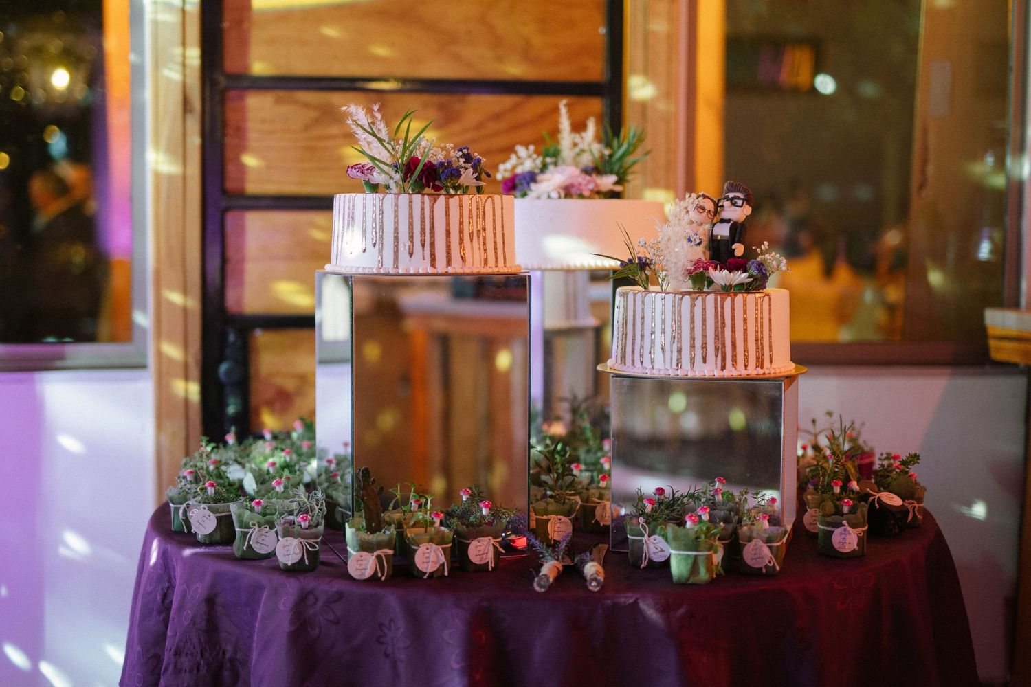 Elegant tiered cake display with copper accents and succulent decorations on dark tablecloth.