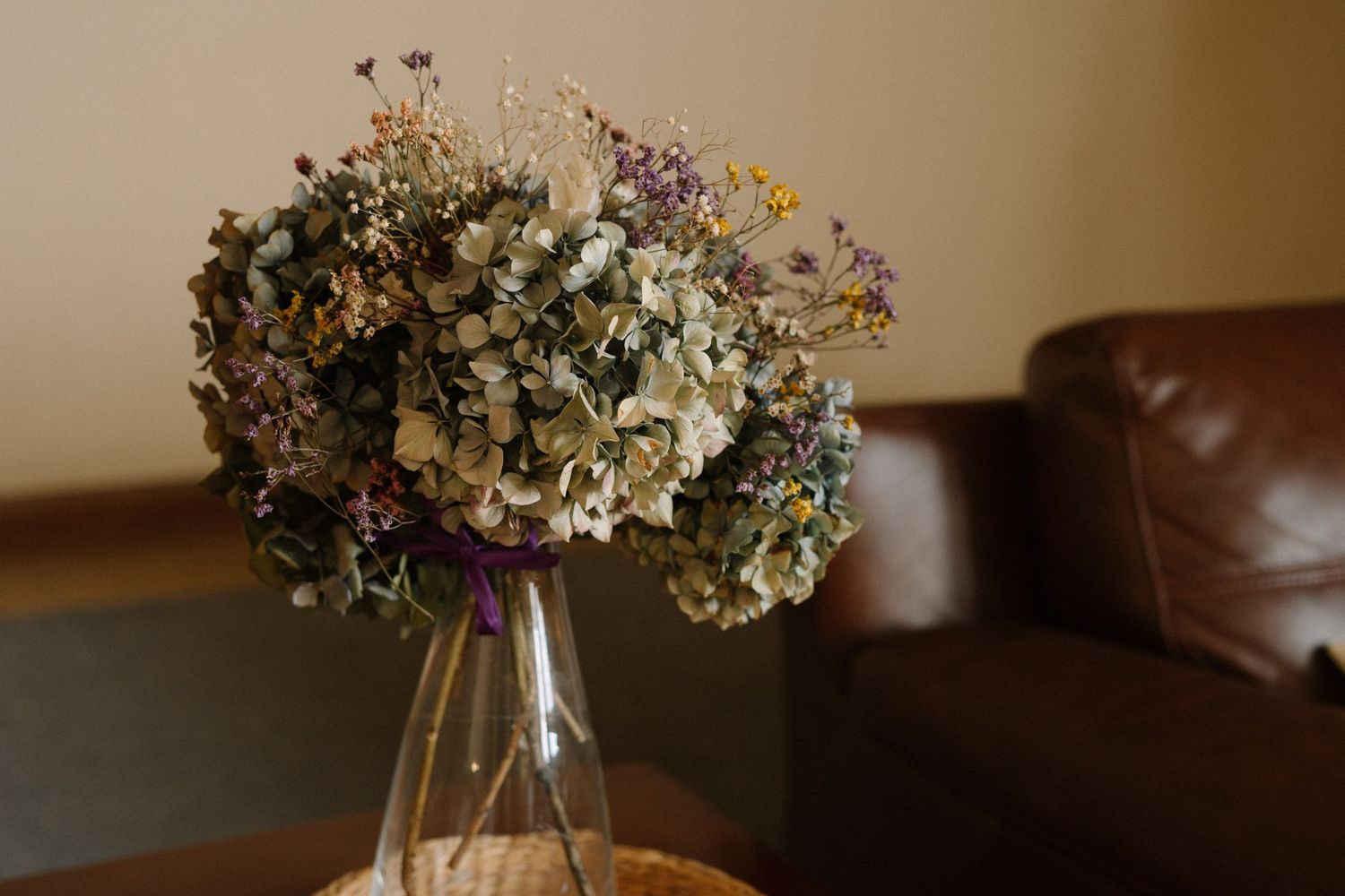 Dried flower arrangement in glass vase featuring mixed pastel-colored blooms.