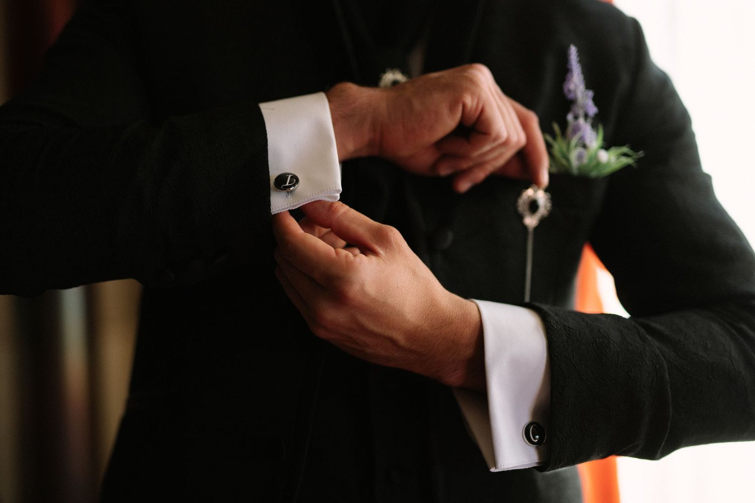 Close-up shot of hands adjusting formal shirt cuffs with cufflinks.