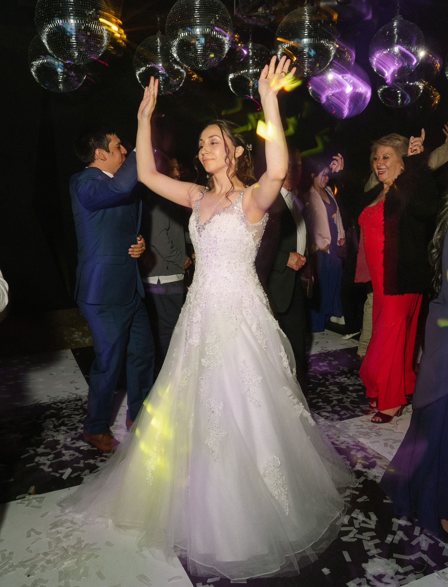 Wedding celebration on a dance floor with disco balls and colorful lighting effects.