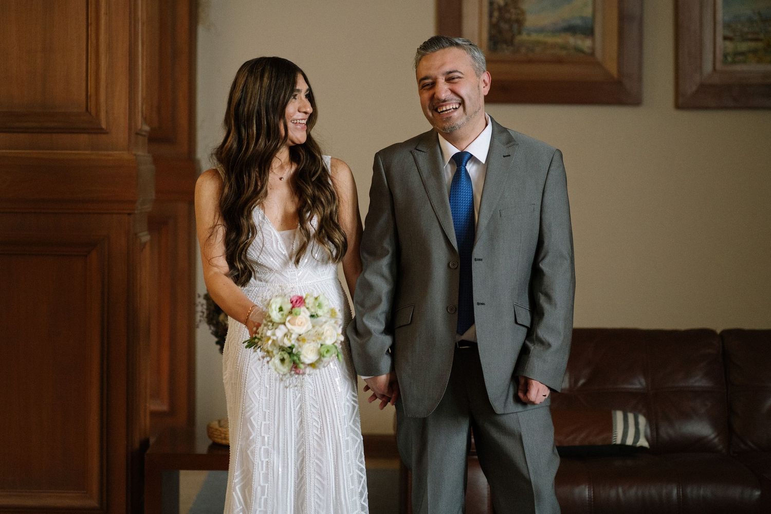 Couple poses together against wooden doors in wedding attire.